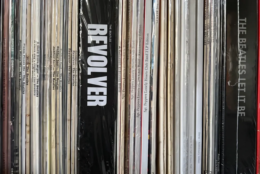 LP spines packed tight on a shelf, The Beatles’ Revolver standing proud of Rubber Soul, A Hard Day’s Night and a run of Sgt. Pepper reissues